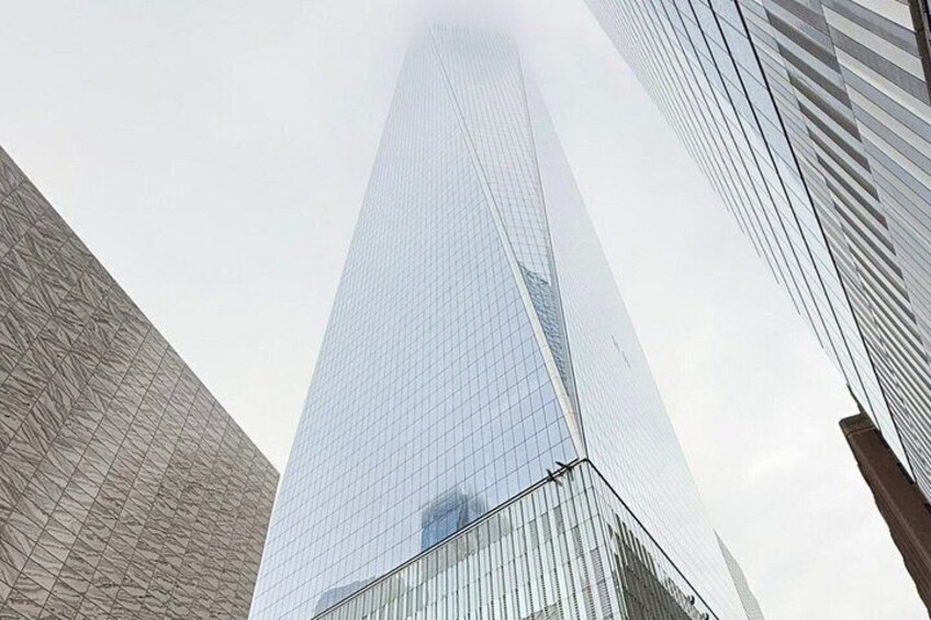 A tall glass skyscraper with a grid-like facade, surrounded by other modern buildings. 2