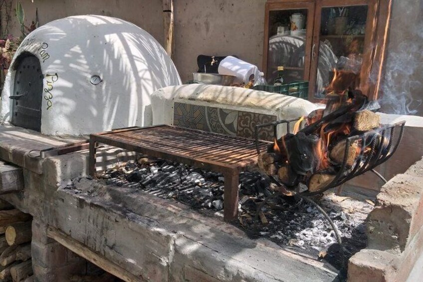 An outdoor cooking area with a grill, a pizza oven, and a fire pit. 4