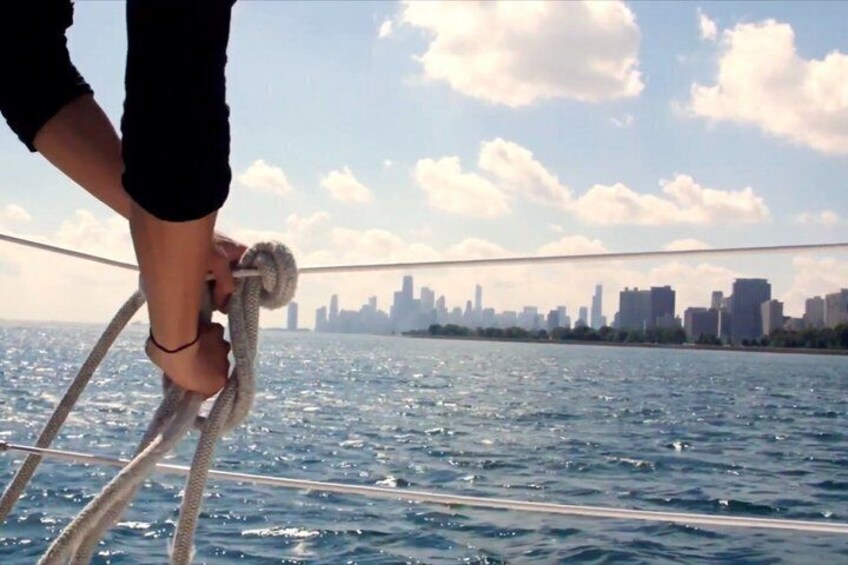 A person holding a rope on a boat with a city skyline in the background. 3