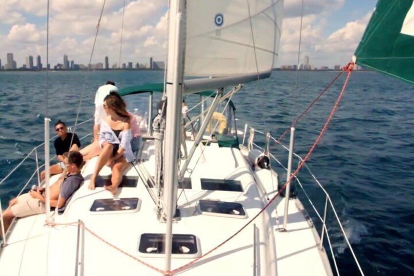 A sailboat with people on deck, a city skyline in the background, and calm waters. 4