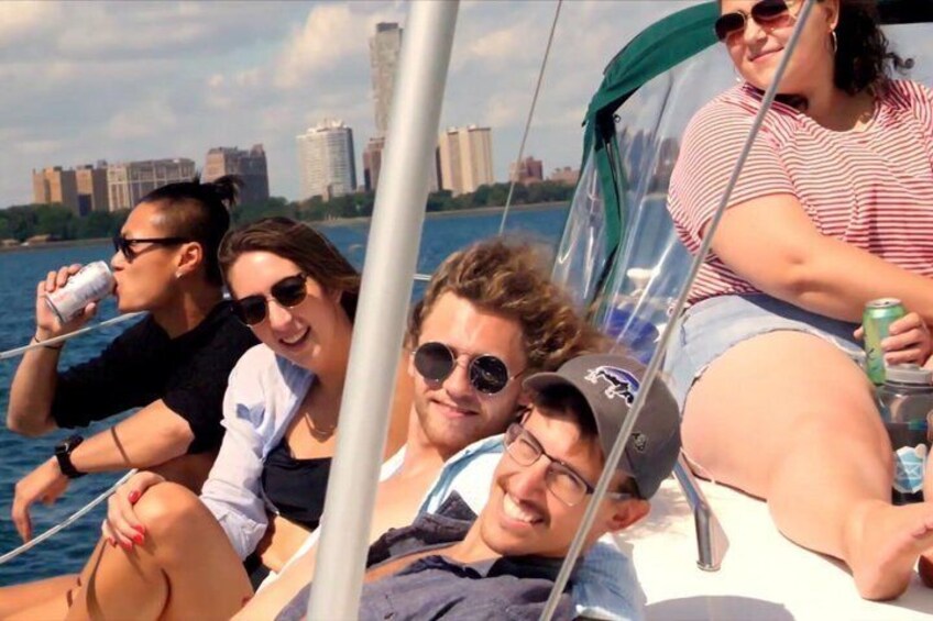 A group of people on a sailboat with a city skyline in the background. 2