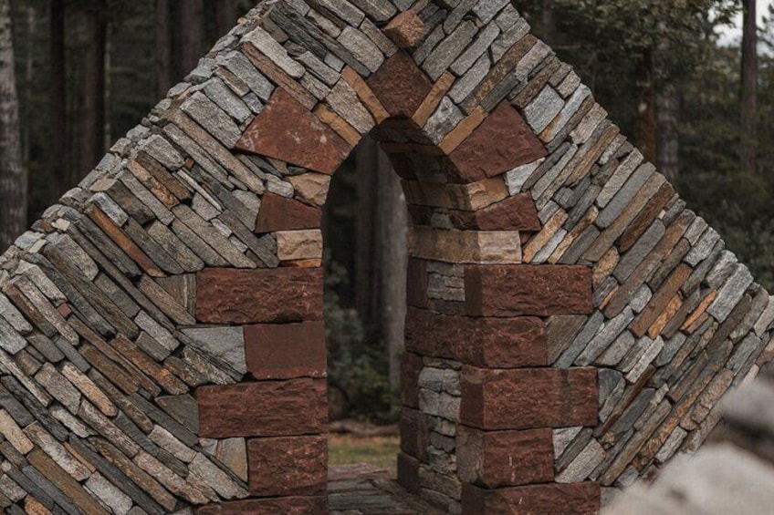 A stone archway with a herringbone pattern, surrounded by a forest. 1