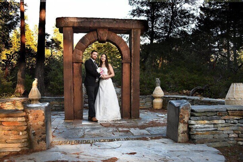 A couple under a wooden archway in a stone garden. 2