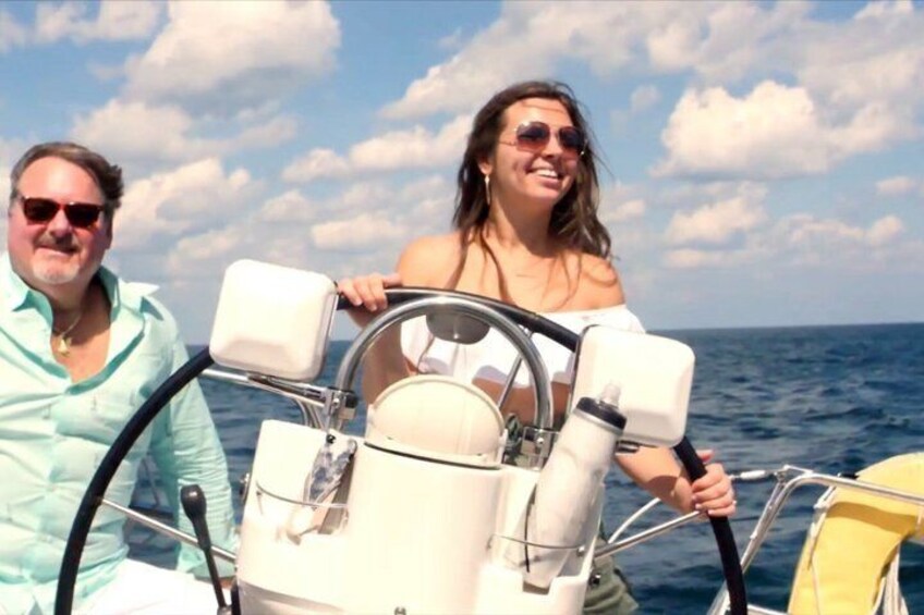 A person steering a boat on the water with a clear sky and clouds in the background. 5