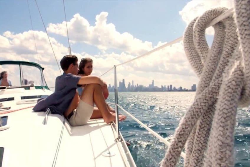 A couple on a sailboat with a city skyline in the background. 1