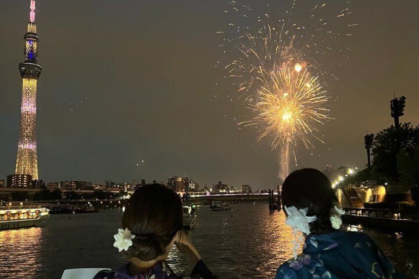 A fireworks display over a city skyline with a prominent tower. 3