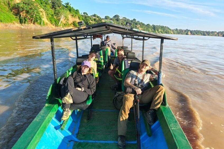 A green boat with passengers on a calm river. 4