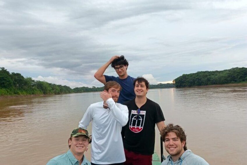 Four people on a boat on a river with a forested landscape in the background. 5