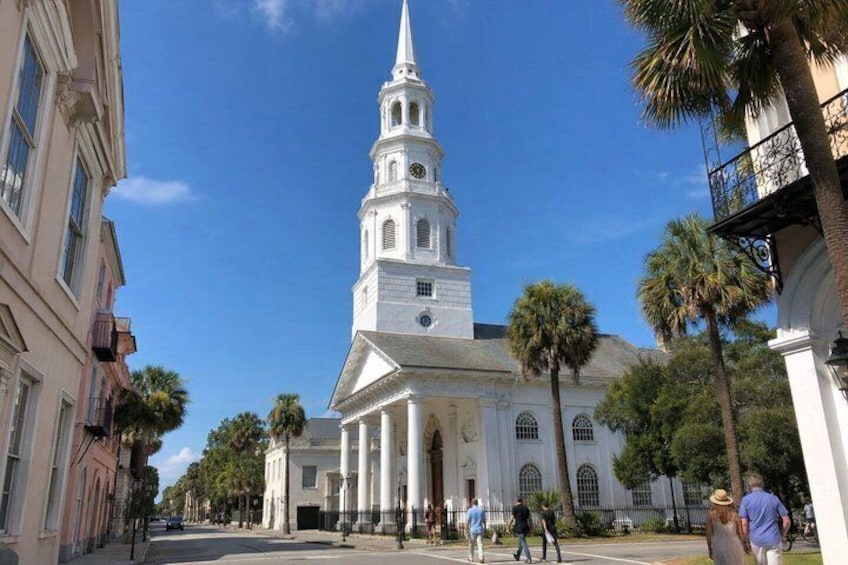A white church with a tall steeple, surrounded by palm trees and pedestrians. 4