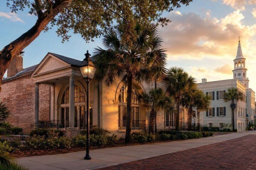 A historic building with a clock tower, surrounded by palm trees and a brick pathway. 1