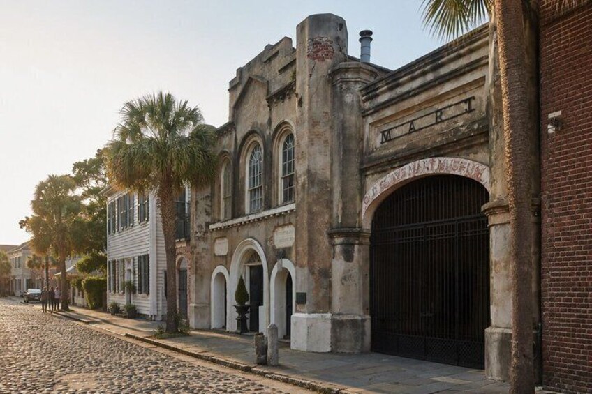 A historic building with a 'MART' sign, cobblestone street, and palm trees. 2