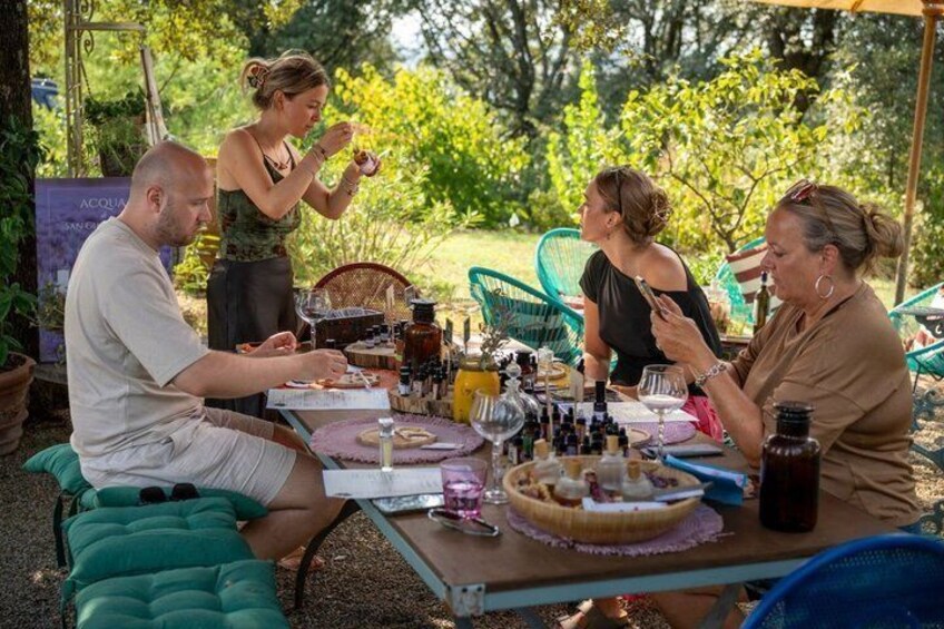A group of people dining outdoors with a table set with food, drinks, and various items. 1