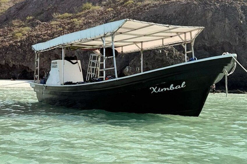 A boat named 'Ximbal' anchored near a rocky shoreline. 1