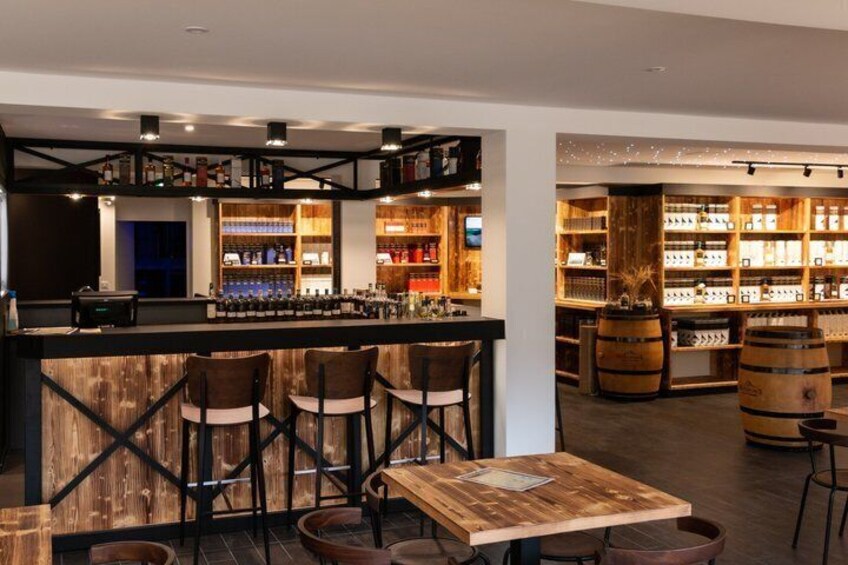 A bar with wooden furniture and shelves stocked with bottles. 2