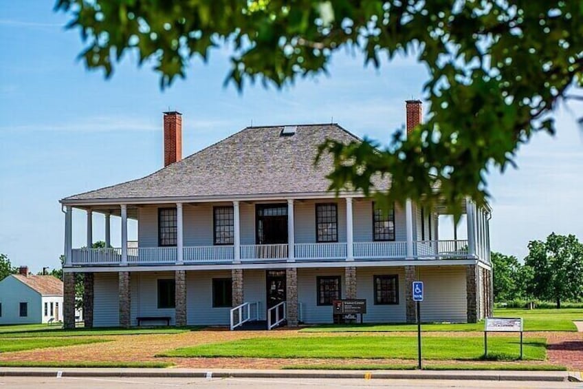 A two-story building with a balcony, a chimney, and a sign indicating a handicap parking space. 2