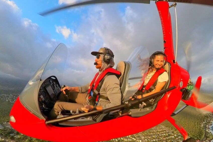 A person in a red helicopter cockpit with another individual seated in front. 2