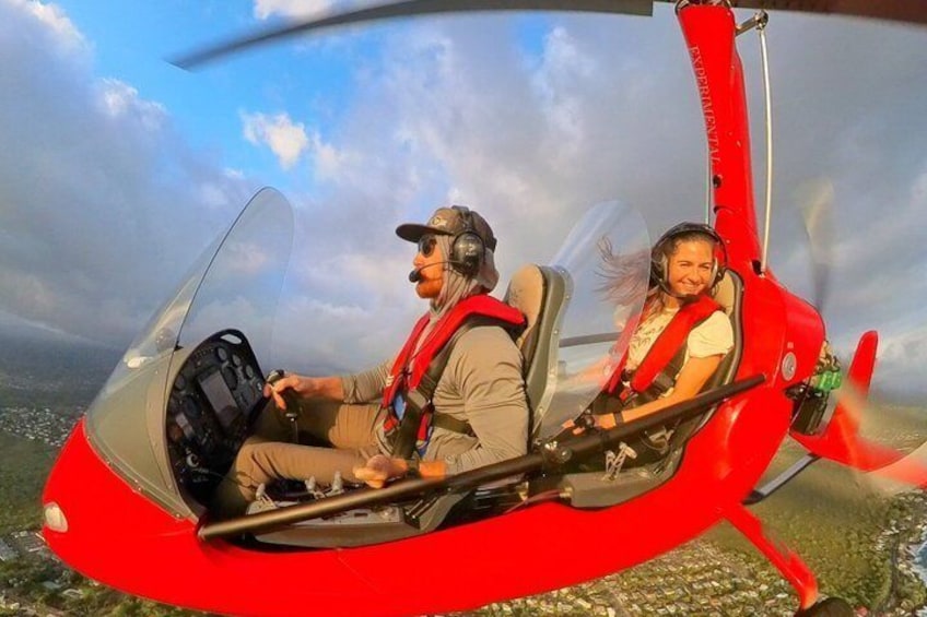 A person in a red helicopter cockpit with another individual seated in front. 4