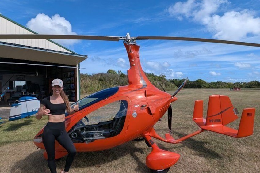 A red helicopter parked on grass with a building in the background. 3