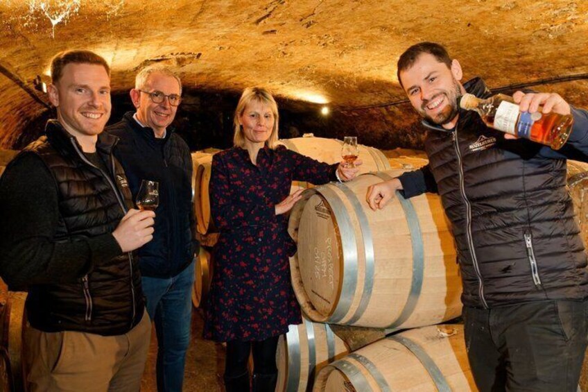 A group of people in a cellar with wooden barrels. 2