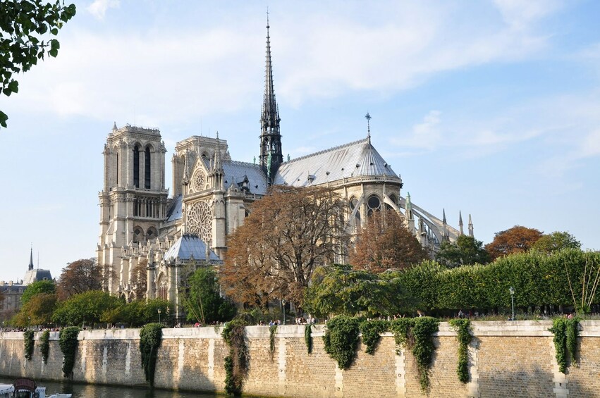 Notre-Dame Cathedral with a spire, a large rose window, and a river in the foreground. 3