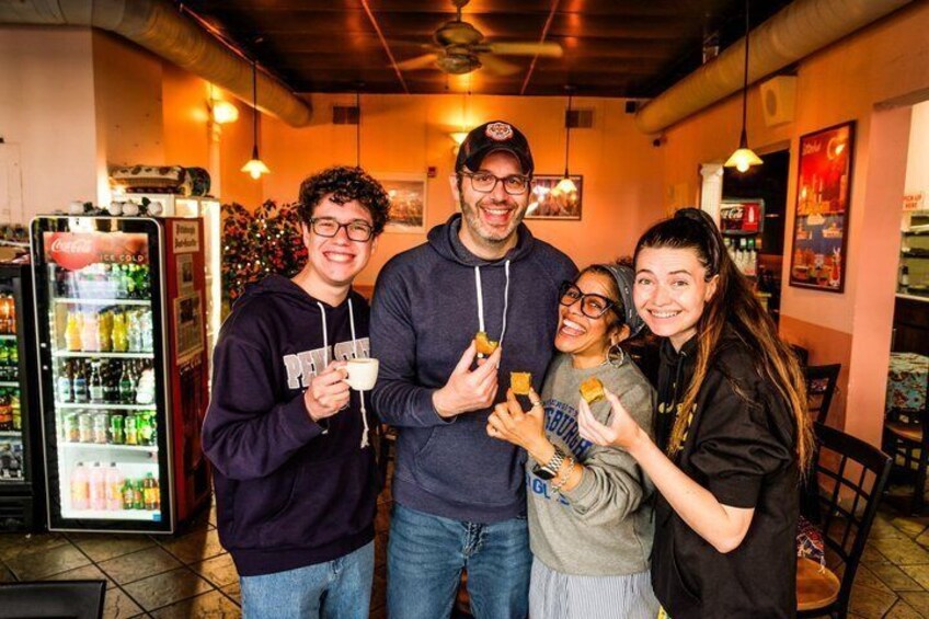 A group of people in a cafe with a Coca-Cola refrigerator and a menu board in the background. 4