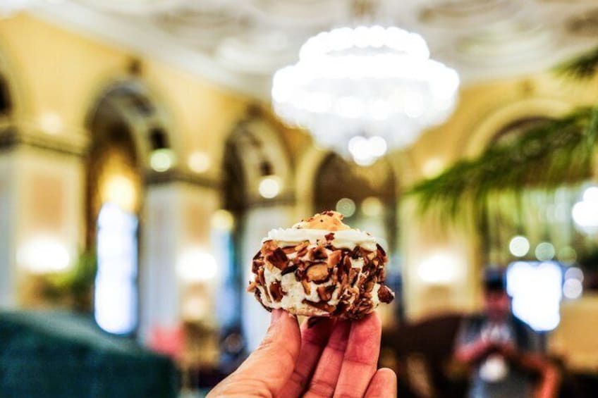 A hand holding a dessert with chocolate and nuts. 2