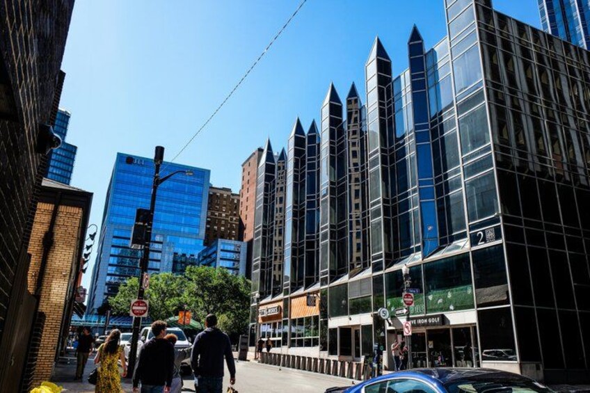 A city street with tall buildings, pedestrians, and a clear sky. 5