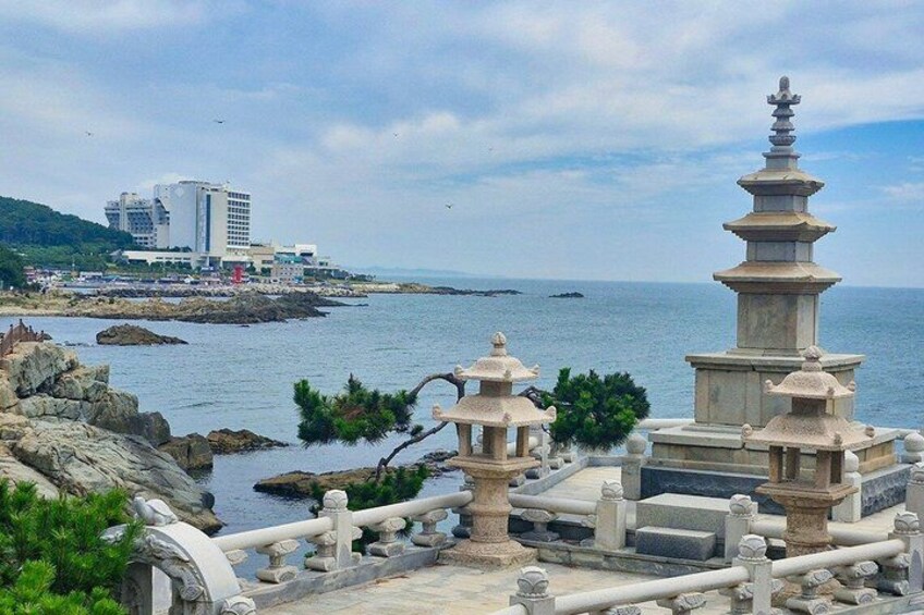 A coastal area with traditional stone lanterns, a modern building, and rocky terrain. 2
