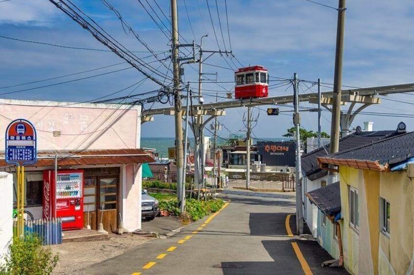 A cable car station with a red cable car, a Coca-Cola vending machine, and a building with a sign in a foreign language. 4