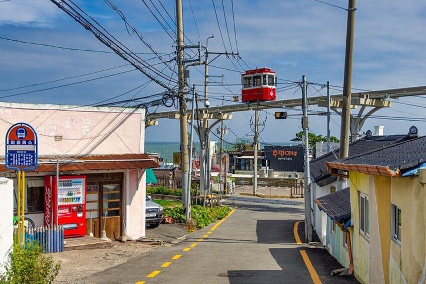 A cable car station with a red cable car, a Coca-Cola vending machine, and a building with a sign that reads 'ABON'. 4