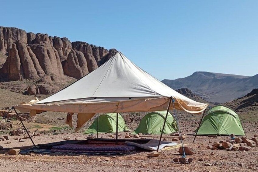 A desert campsite with a large tent and two smaller tents. 3