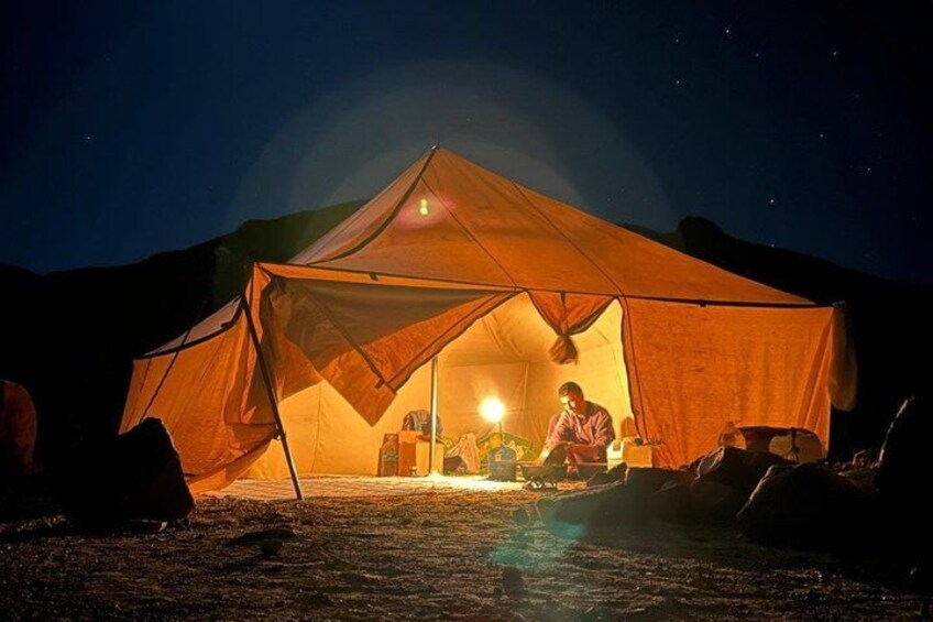 A tent with a person inside, a campfire, and a starry night sky. 2