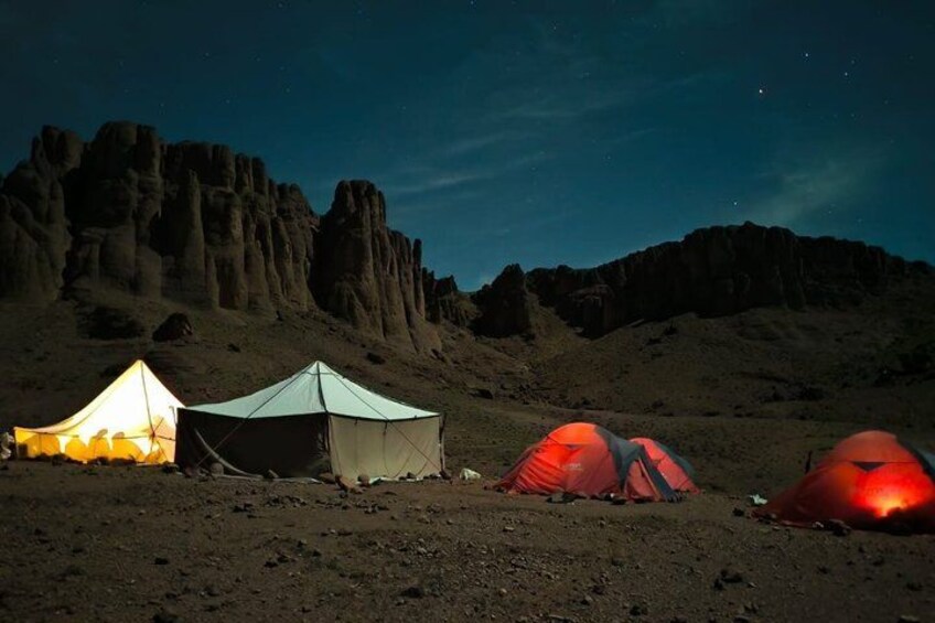 A desert landscape with tents and rocky mountains at night. 3