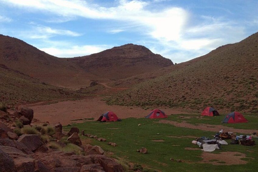 A mountainous landscape with red tents and camping gear. 4