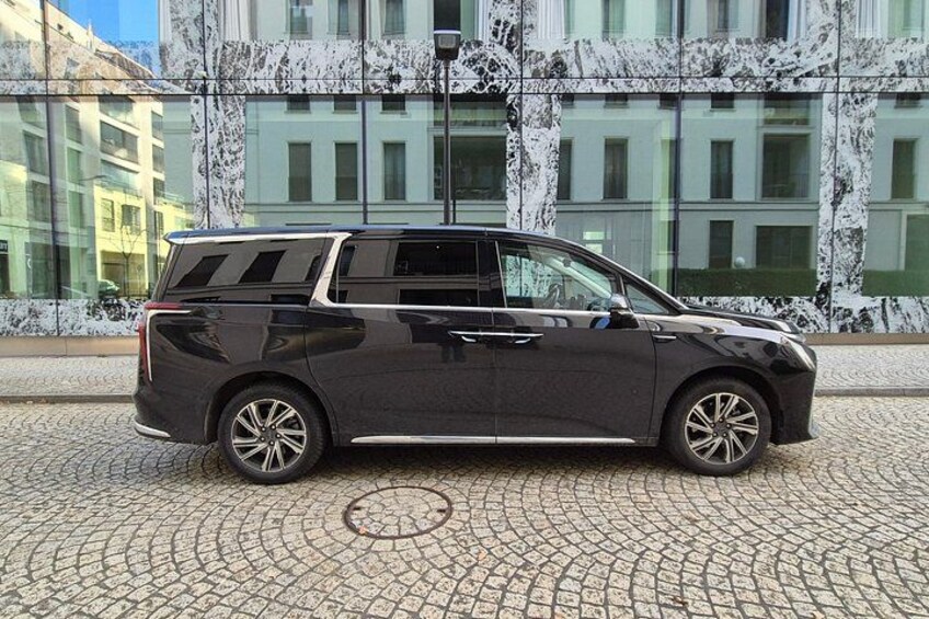 A dark-colored SUV parked on a cobblestone street in front of a building with a marble facade. 3