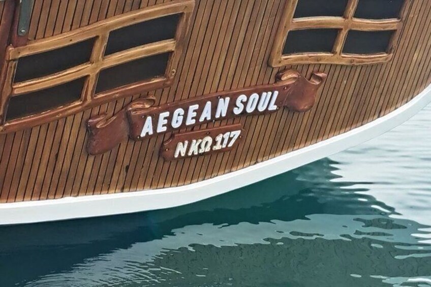 A wooden boat with the text 'AEGEAN SOUL' and 'NK0.117' on its side. 1