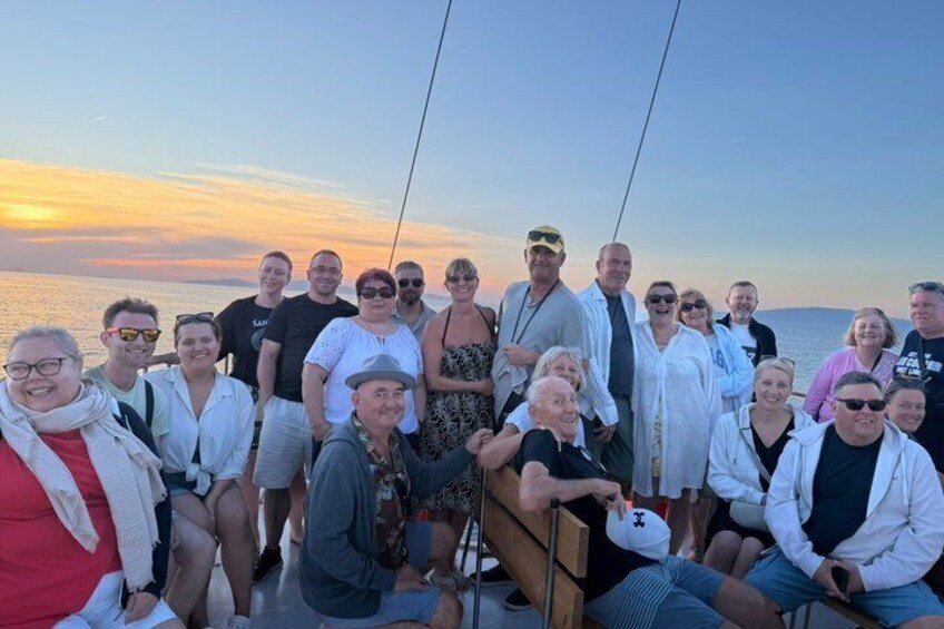 A group of people on a boat with a sunset in the background. 4