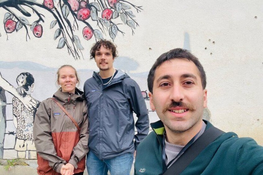 Three people standing in front of a mural with fruit and leaves. 5