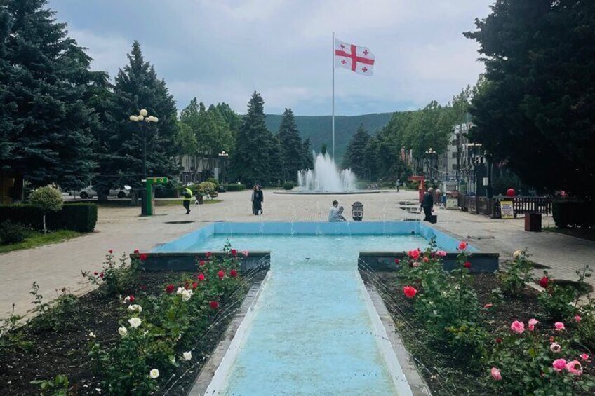 A fountain, a flag, and a garden with flowers. 2
