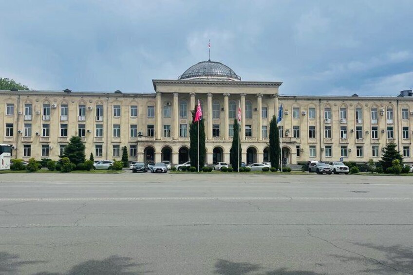 A large, classical building with a dome, multiple flags, and a parking lot in front. 4