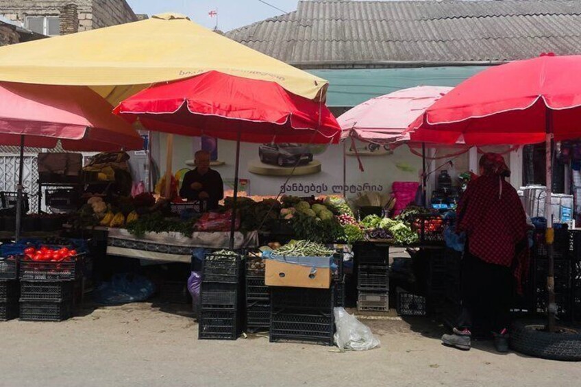 A street market with vendors under red and yellow umbrellas selling fruits and vegetables. 5