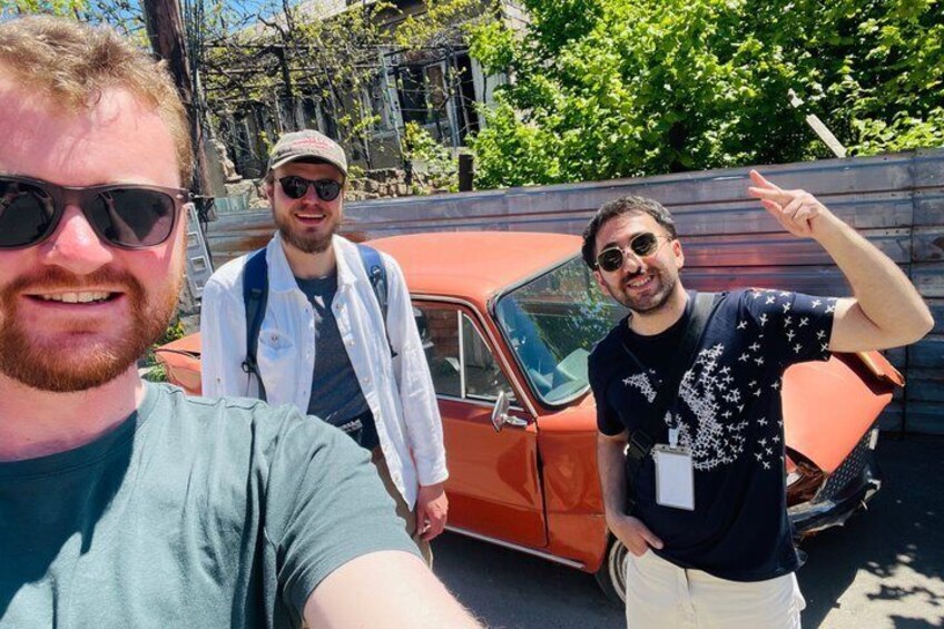 Three people standing in front of a vintage car. 4