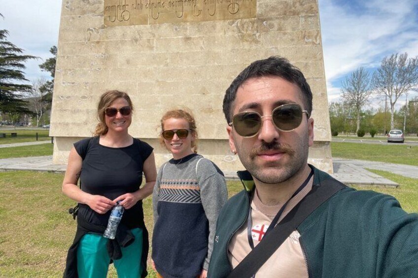 Three people standing in front of a monument with inscriptions. 2
