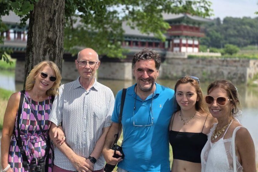 A group of people standing in front of a traditional building with a water body in the background. 5