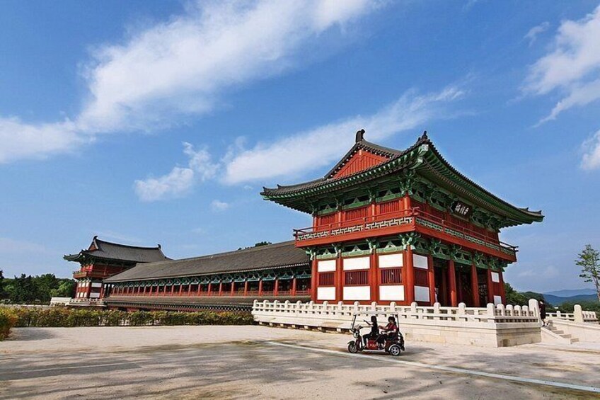A traditional red and green building with a tiled roof, surrounded by a white fence and a paved area. 4