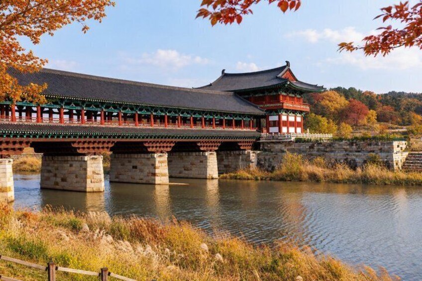 A traditional Korean bridge over a calm river, surrounded by autumn foliage. 4
