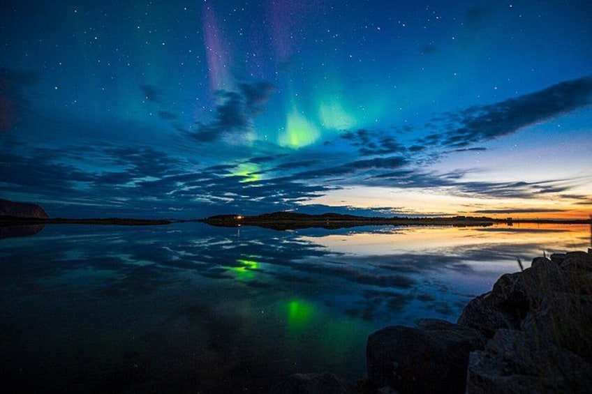A night sky with aurora borealis over a calm lake reflecting the sky. 2
