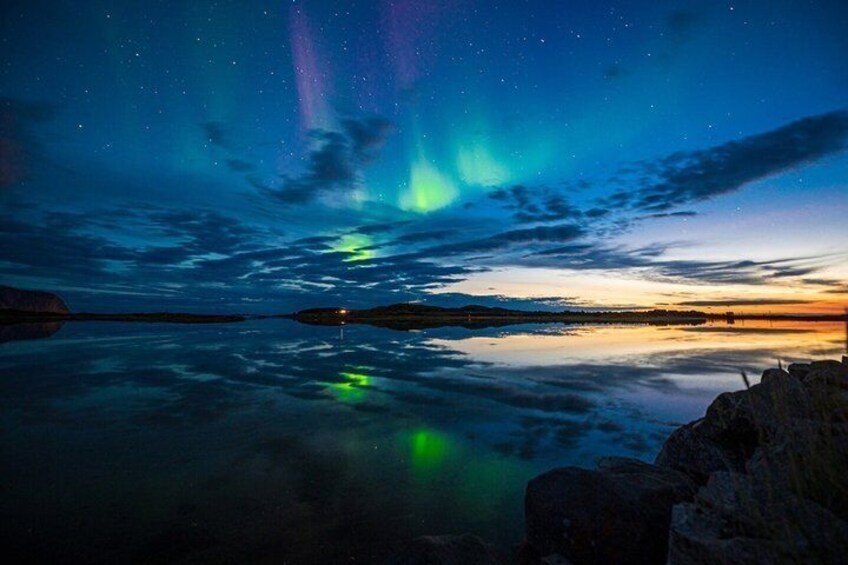 A night sky with aurora borealis over a calm lake reflecting the sky. 2