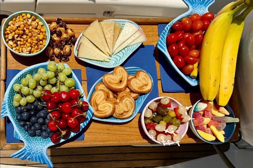 Un plateau en bois contenant divers aliments, notamment des raisins, des cerises, du pain et des bananes. 2
