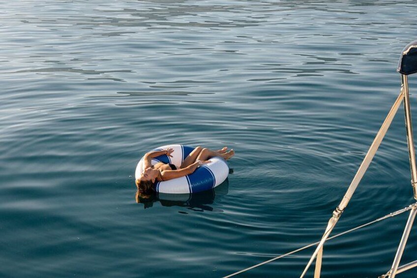 Une personne flotte sur un flotteur gonflable bleu et blanc, dans une eau calme. 3